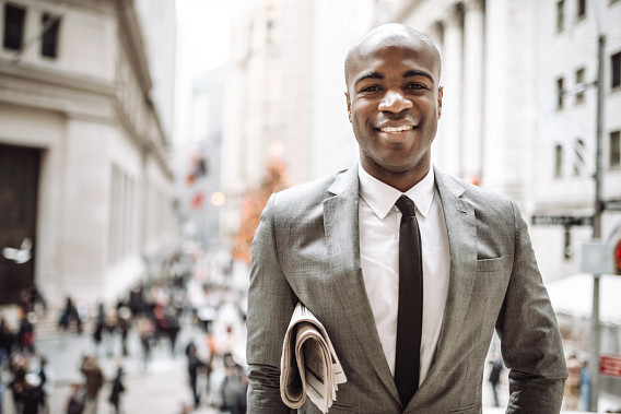 man in suit outside with newspaper under arm