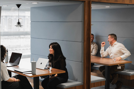 Two groups of colleagues working together in meeting booths