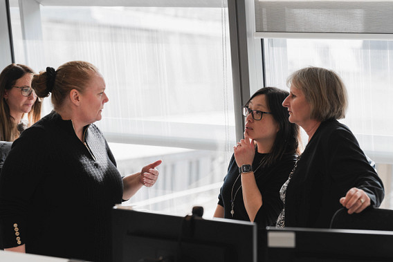Three colleagues stood in an office talking